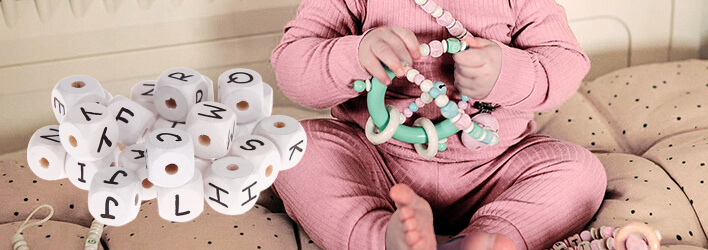 Drewniane kostki z wytłaczanymi literkami w kolorze białym idealne na podarunek dla niemowlęcia z ułożonym imieniem dziecka 