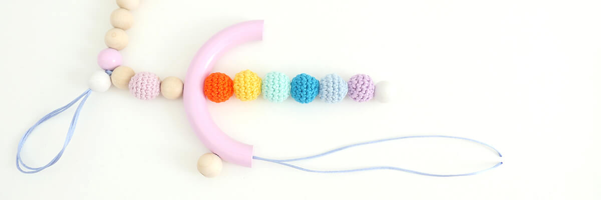 step-by-step instructions wooden bead rainbow garland: passing cord through half ring's side hole